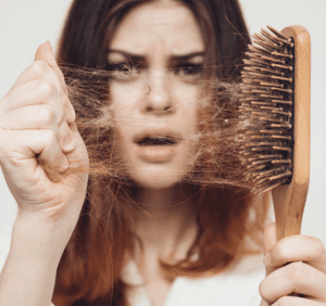 mujer quitando cabellos que han quedado en un cepillo del pelo.